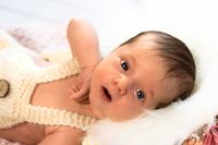 Süßes Neugeborenes in Latzhose schaut in die Kamera, Fotoshooting in Kaufbeuren